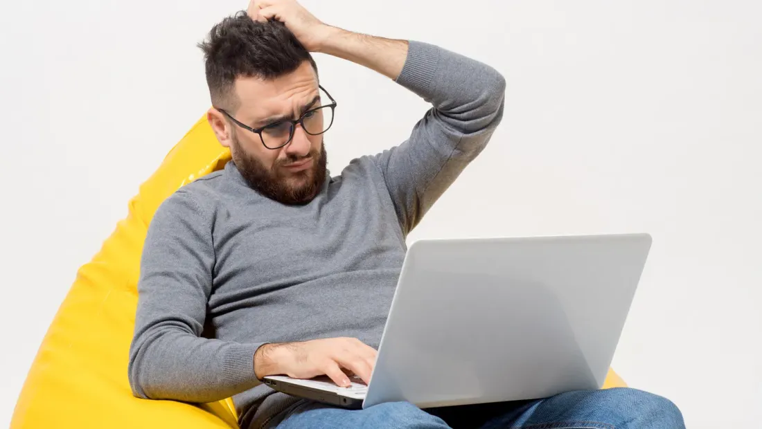 Frustrated man sitting in a chair trying to figure out website maintenance on his own