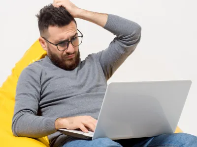 Frustrated man sitting in a chair trying to figure out website maintenance on his own
