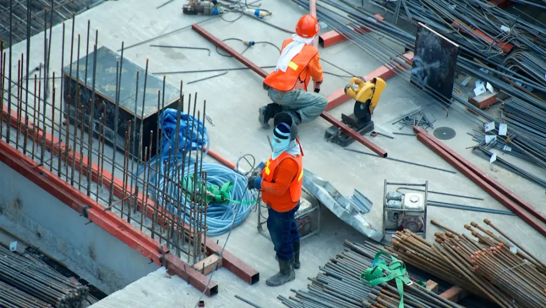 Construction worker on a job site reviewing plans with a residential build in progress
