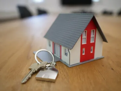 A house key on a keychain resting on a wooden surface with warm lighting