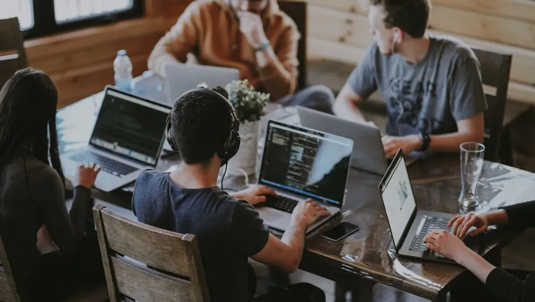 Team of remote workers collaborating around a laptop at a shared table