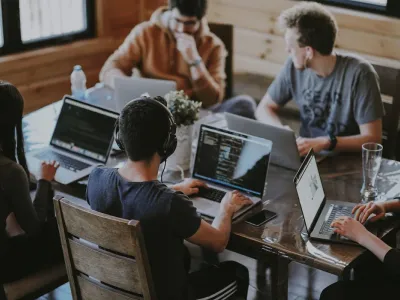 Team of remote workers collaborating around a laptop at a shared table