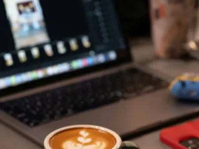A laptop on a desk showing website analytics alongside a notebook and coffee cup