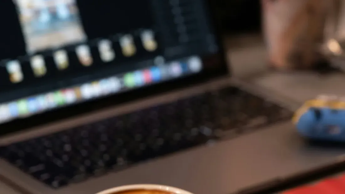 A laptop on a desk showing website analytics alongside a notebook and coffee cup